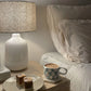 Cosy bedside scene featuring a mug of Real Rad Food Rad Sleep sleepy hot chocolate beside raw slices and a warm bedside lamp for a relaxing nighttime ritual