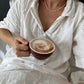 Women in bed holding a mug of Real Rad Food Rad Sleep sleepy hot chocolate in bed as part of a calming nighttime wellness routine